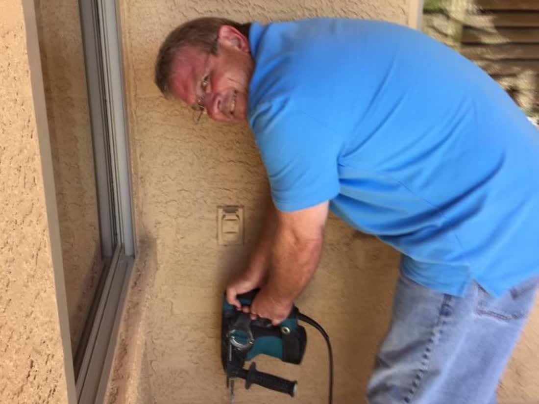 A member of the Peterson family working on the exterior wall of an East Valley home