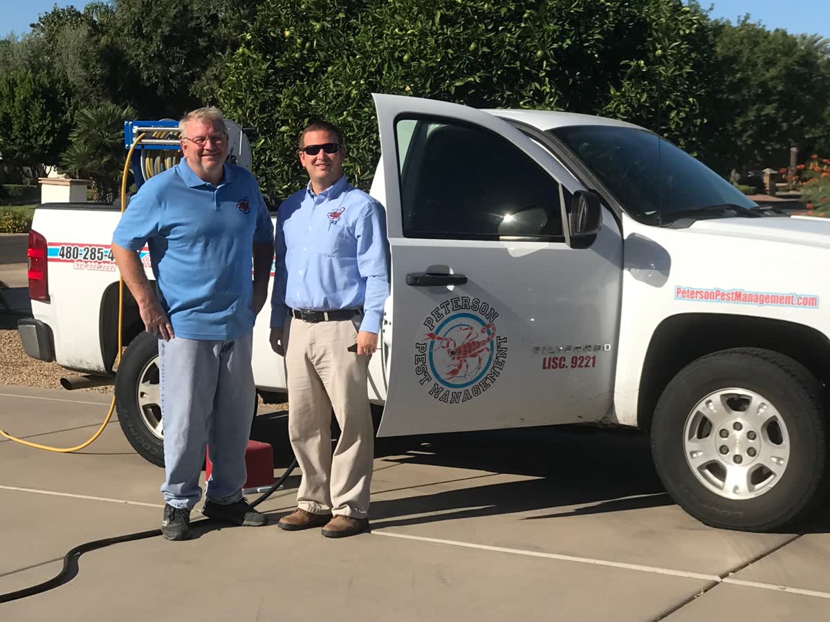 Two generations of the Peterson family beside a Peterson Pest Management service truck