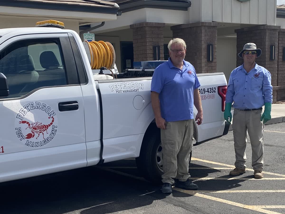 Two members of the Peterson Pest Management team beside a service truck
